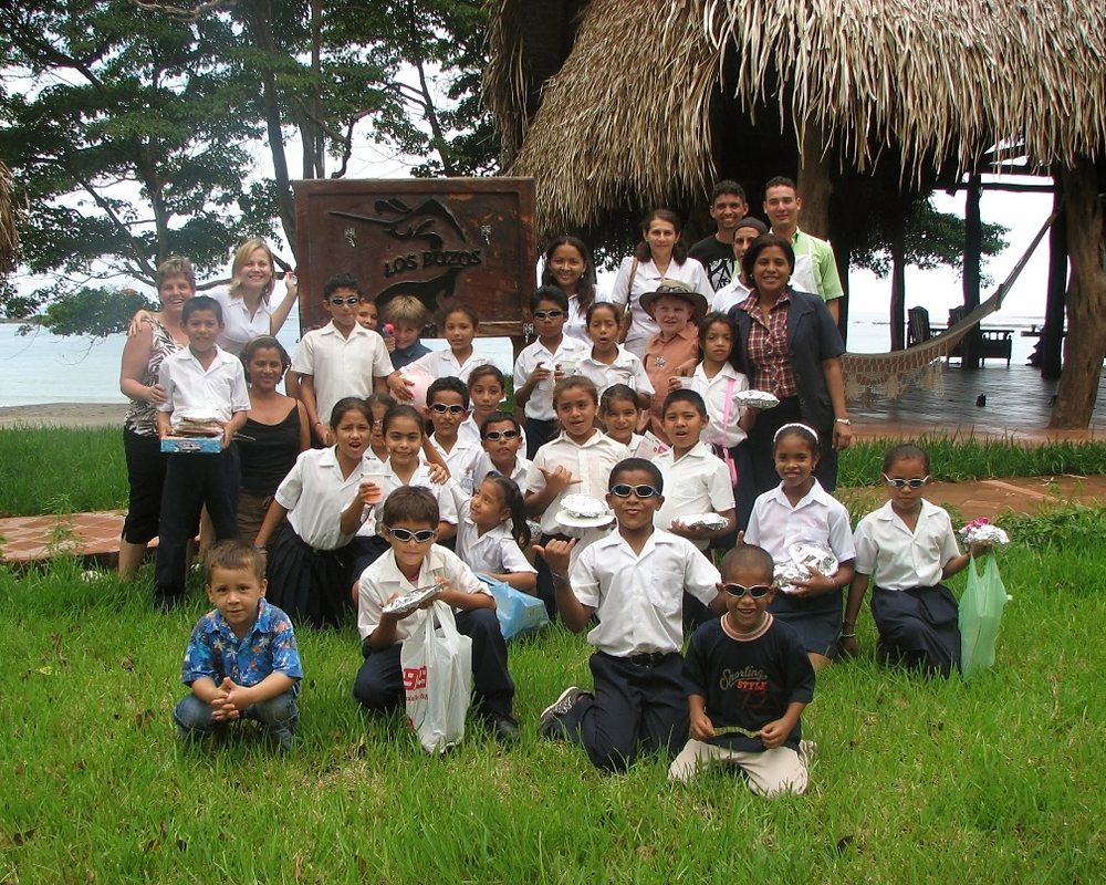 Children from the local public school gathered at a Los Buzos party in the early years, in front of the carved Los Buzos sign on the Azuero Peninsula, Panama